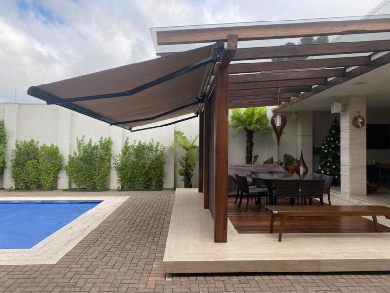 toldo retratil branco com braco preto perto de uma piscina